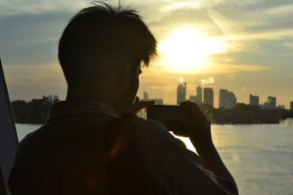 a man takes a photo of the sunset over the bangkok skyline