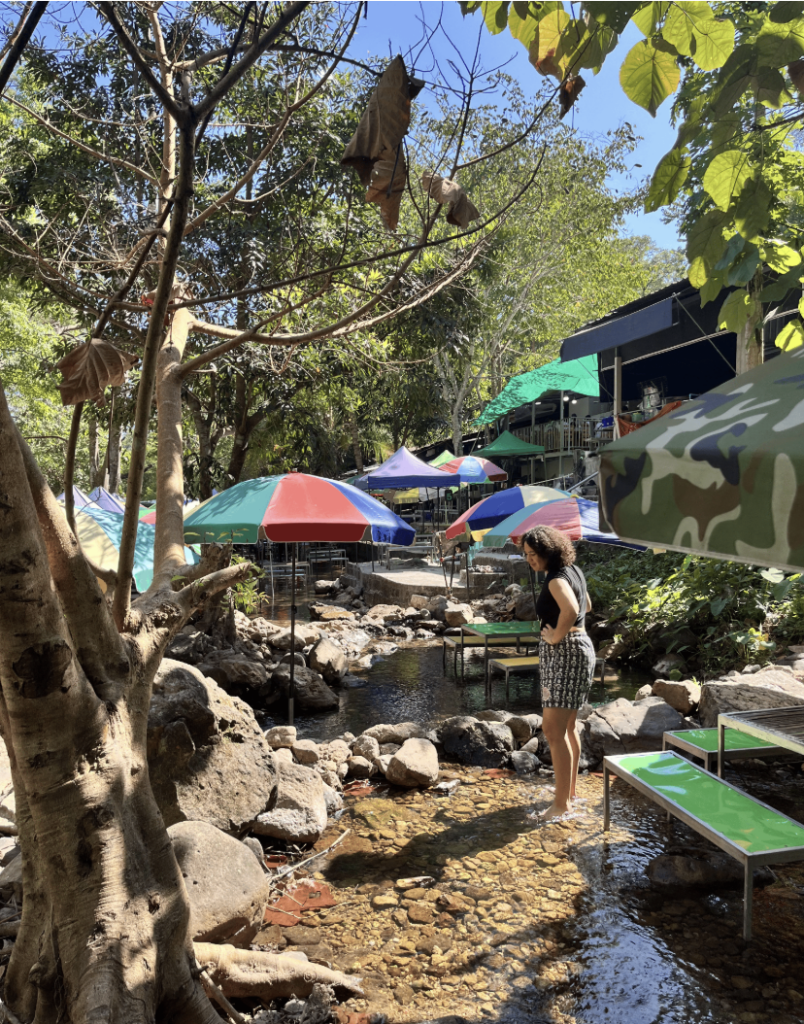 A teacher stands in the water by a cafe. discovering hidden Thailand