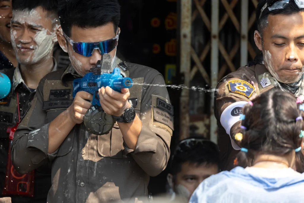 a policeman shoots a small water pistol during songkran in Bangkok
